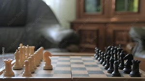 A man moves chess pieces on a chessboard. Against the background of vintage old things. Game of Chess.Player makes a move, developing chess strategy, play board game with opponent.