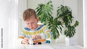 Little boy performing or studying science with wires, connections. Electronic experiment. The child is experimenting at home. Stock Video