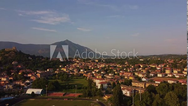 Aerial sunset view of Avigliana, Italy, Piedmont , Turin,Italy A beautiful town with a medieval castle and red-roofed houses, surrounded by the green hills of Susa and trees on a sunny day.