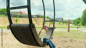 Cute little girl having fun on a swing outdoors on sunny spring day. Spring outdoor activities for kids.