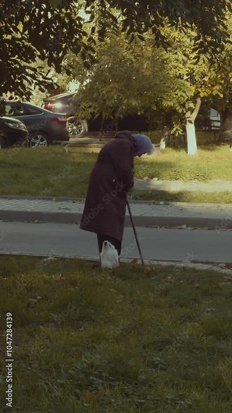 old sick woman pensioner with a cane on a walk on the street. Poor old age