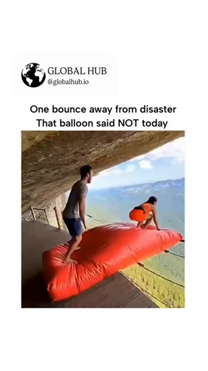 GLOBAL HUB on Instagram: "The post features a 10-second video of a woman bouncing on a red inflatable mat teetering on a cliffside platform in a mountainous area, narrowly avoiding a fall into the abyss, captioned to highlight the thrill of the near-miss. Posted on December 23, 2025, by @casmirtheking_ , it garnered over 2.4 million views and 1,400 likes within hours, sparking debates in replies about whether the footage is genuine or AI-generated, with the author insisting it's real. The stunt