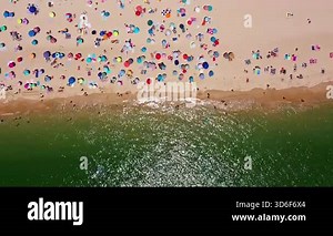 Sunny beach scene, Colorful umbrellas fill shoreline, Bustling seaside with lively sunbathers and umbrellas, Vivid coastal landscape showing crowded beach with umbrellas and waves