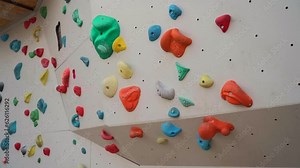 Artificial climbing wall for indoor training with colored handles and route markers for beginners and children. Gears and climbing wall for kids outdoor activities. Bouldering track on artificial wall