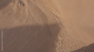 Close-up texture of a sandy beach with soft waves gently lapping the shore, capturing the tranquil and serene interface between land and water.