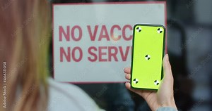 Woman using smartphone with chroma key, digital health passport app with covid-19 certificate. Proof of vaccination. No vaccine no mask no entry service. Green screen