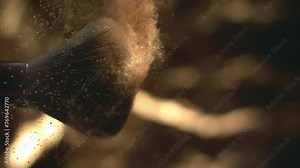 Super slow motion shot of makeup brushes touch each other and making particles. Golden shiny face powder shake at 1000 fps. Beauty make-up glitter flying in high speed. Close up luxury vertical video