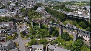 Drone view of a train riding along the Royal Albert Bridge to Saltash in Cornwall, UK, highlighting historic engineering