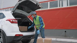 Volunteer wearing a mask and gloves delivers parcels. Online shopping during the covid-19 coronavirus pandemic. Contactless delivery of goods by courier service. Delivery during the coronavirus period
