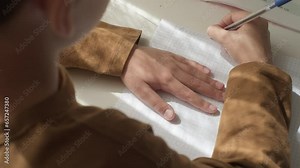 Close-up shot of boy solving math problem. Concentrated kid school boy studying lesson writing with pen at home. Primary class pupil write homework