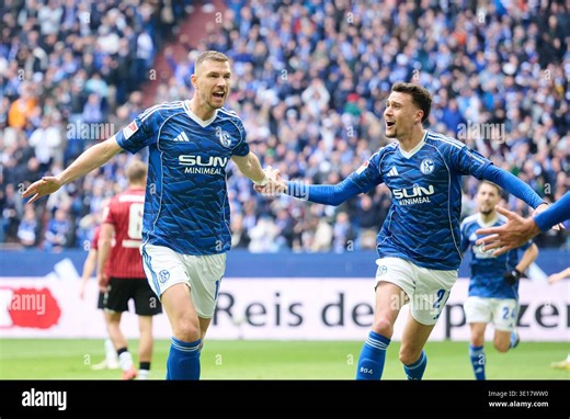 15 March 2026, North Rhine-Westphalia, Gelsenkirchen: Soccer, Men: Bundesliga 2, FC Schalke 04 - Hannover 96, Matchday 26, Veltins Arena. Edin Dzeko (FC Schalke 04, l.) celebrates his goal for 1:0 with Dejan Ljubicic (FC Schalke 04). Photo: Bernd Thissen/dpa - IMPORTANT NOTE: In accordance with the regulations of the DFL German Football League and the DFB German Football Association, it is prohibited to utilize or have utilized photographs taken in the stadium and/or of the match in the form of 