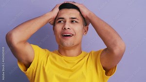 The positively surprised man screaming and clutching his head while standing in the purple studio