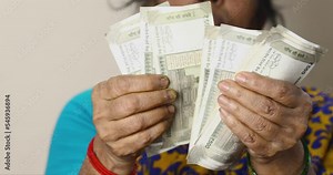 Close up of female hands counting a 500 rupees notes of Indian money by hand, a woman counts cash. A woman counting new Indian money. Indian Rupee, Home Finance concept. Selective focus