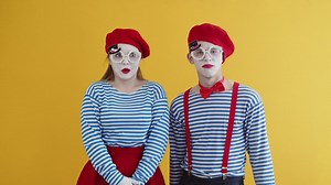 Two mimes having a laugh in costume on a yellow background - Free Stock Video