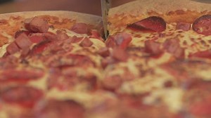 Cutting a pizza with a pizza cutter - Free Stock Video