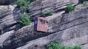 Cart moving on wires between mountains in Meteora, Greece to deliver supplies to hilltop monastery. Cable car suspended in the air. Meteora lift car