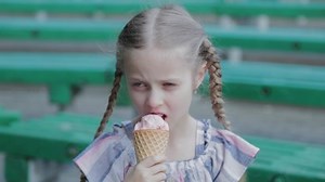 Beautiful happy girl eating ice cream in the park on a bench.