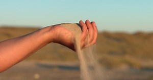 Sand slipping through fingers in slow-motion
