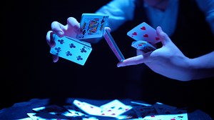 Close-up, Hands of a Magician Performing Tricks with a Deck of Cards. Blue Lighting. Conjurer Shows Focus. Camera Quickly Rotates 360 Degrees.