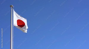 Real-time video of the Japanese National Flag waving in the wind against a cloudless blue sky in Japan where Tokyo is the host city for the international sporting events in summer 2020.