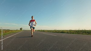 Front view of strong male athlete running, training endurance in road in summer. Man in sportswear and sneakers taking part in marathon, exercising. Concept of health and sport.