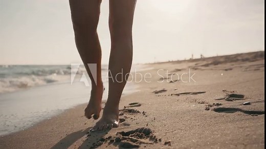 Video of closeup of young woman in bikini walking on the sand of the beach