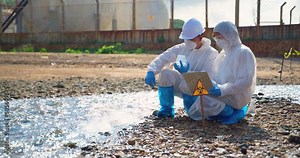 Team scientist in protective suit, mask and gloves collect sample of fish and dirty water from factory took a sample of waste water for analysis. Pollution and environment problems