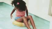 African girl is swimming indoors at swimming pool. She is wearing...