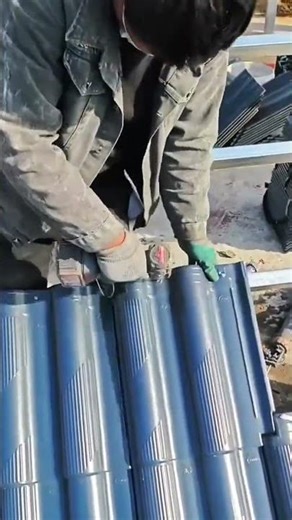 Installing blue roof tiles using a power drill on a metal structure