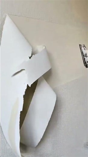 removing cream wallpaper from indoor walls using a wide metal scraper tool to reveal the surface