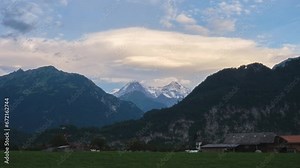 Layers of lenticular clouds above Swiss mountain peaks in the Alps - evening timelapse. Switzerland, Europe, nature, landscape, rural, tourism.