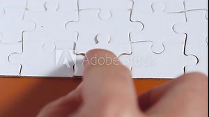 Hand completing a final pieces of jigsaw puzzle.