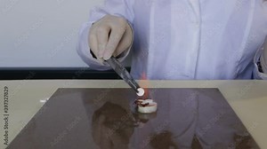 Chemical reaction of Pharaoh's serpent demonstration: conversion of Calcium gluconate to Hexamine fuel tablet. A round white tablet rolls down due to artificial thermal streams of fire. Close-up, real