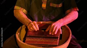 Folk musicians perform intimate gig. Close up shots of an instrumentalist playing a mbira aka marimbula, a vintage finger piano originating from Africa. Played during an intimate concert.