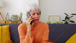 Senior woman making online shopping using credit card and talking on phone. Online payment and banking concept.