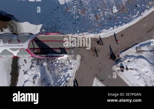 Calgary, Alberta, Canada. March 2, 2026. Top down aerial panning view of the iconic red Peace Bridge crossing the frozen Bow River in winter Stock Video Footage - Alamy
