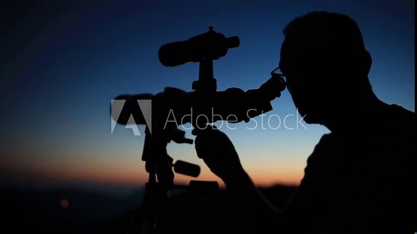 Astronomer looking at the stars, planets, Moon and celestial objects with a telescope.