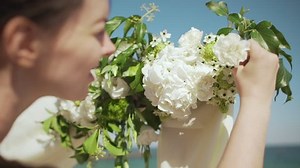 Close up footage of brown-haired female decorating wedding arch with flowers in slowmotion. Back view