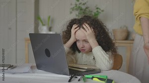 Unhappy young girl sitting at desk, suffering from pressure while doing homework with mother at home. Angry mom scolding stressed daughter for bad school results, parent and children conflict concept.