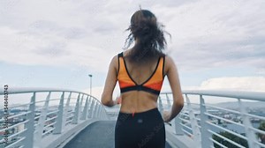 Fitness, earphones and woman in city running while streaming motivation music, radio or podcast. Healthcare, sports and female runner listening to audio and training for marathon on street outdoors.