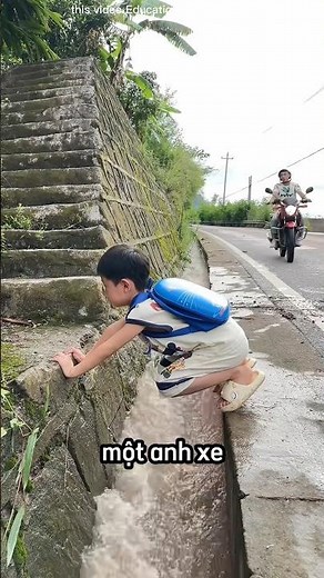 The kind motorbike taxi driver helped the little boy cross the drain.