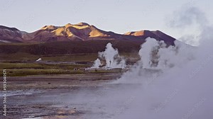Water steam rising at El Tatio Geyser Field with mountains in the background. Third-largest geyser field in the world.