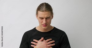 handsome well-built caucasian man is having a heart pain. Male touching his chest because of heart attack. Isolated on gray background. breathe in and breath out to relief pain, respiratory gymnastics