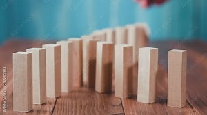 Domino effect. Wooden dominoes falling in sequences, chain reaction on a wooden table.