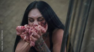 Terrible zombie woman eating raw brains and meat. The girl's face is covered in blood