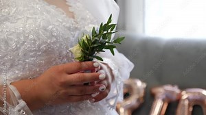 The bride is holding a beautiful rose in her hands. Preparation for the wedding ceremony.