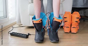 Man places electric heaters inside ski boot liners, at home, used to dry wet shoes, gloves. Ski boot warmer, dryer.