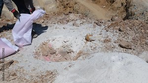 Pouring explosives into dug holes for quarry explosion. Explosive dust dumping into the excavated hole.