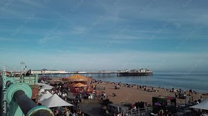 Busy day at a British seaside funfair and beach in Brighton. Visitors enjoy sunny weather, outdoor dining, and attractions in a relaxed atmosphere.