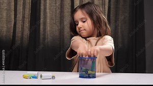Little girl collecting old batteries in a container for recycling used batteries